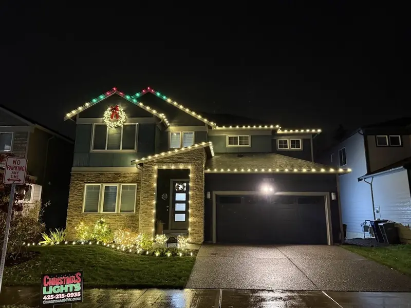 Home with a lit roofline plus wreath and accent lighting