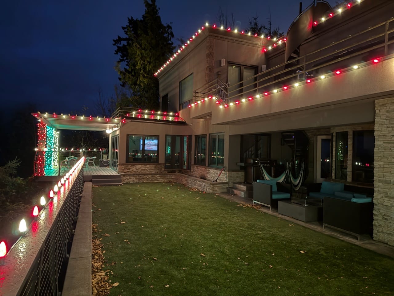Modern home with custom red and white roofline lighting and deck accents