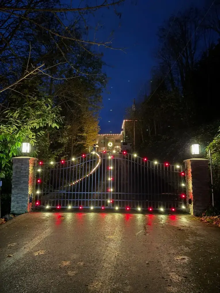 Estate gate with red accent lights and warm white uplighting