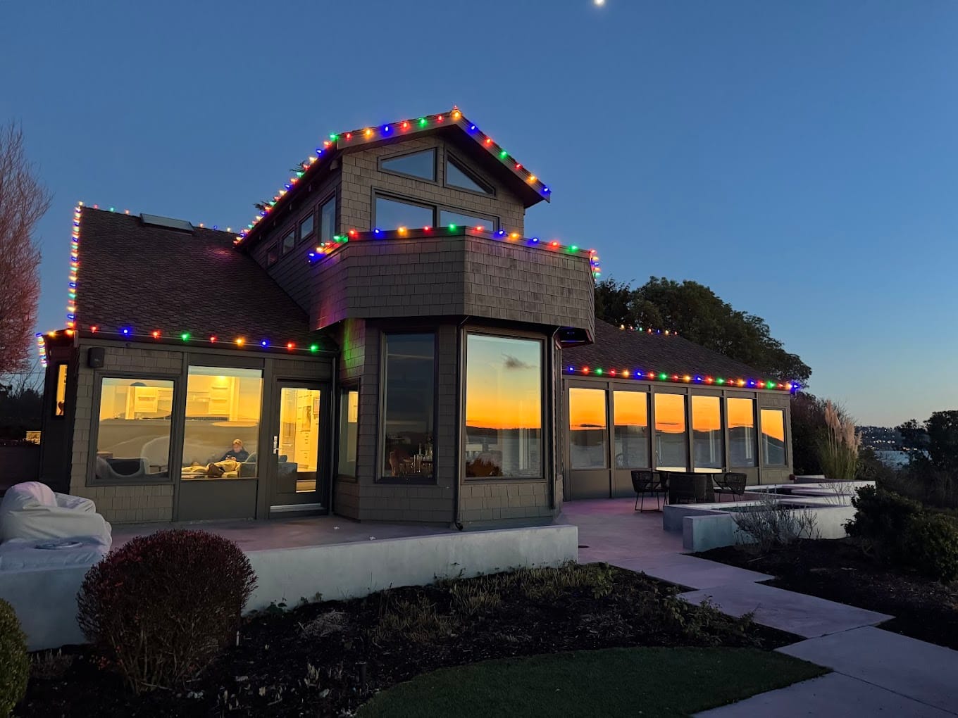Glass home with multicolor rooflines at dusk with sunset backdrop