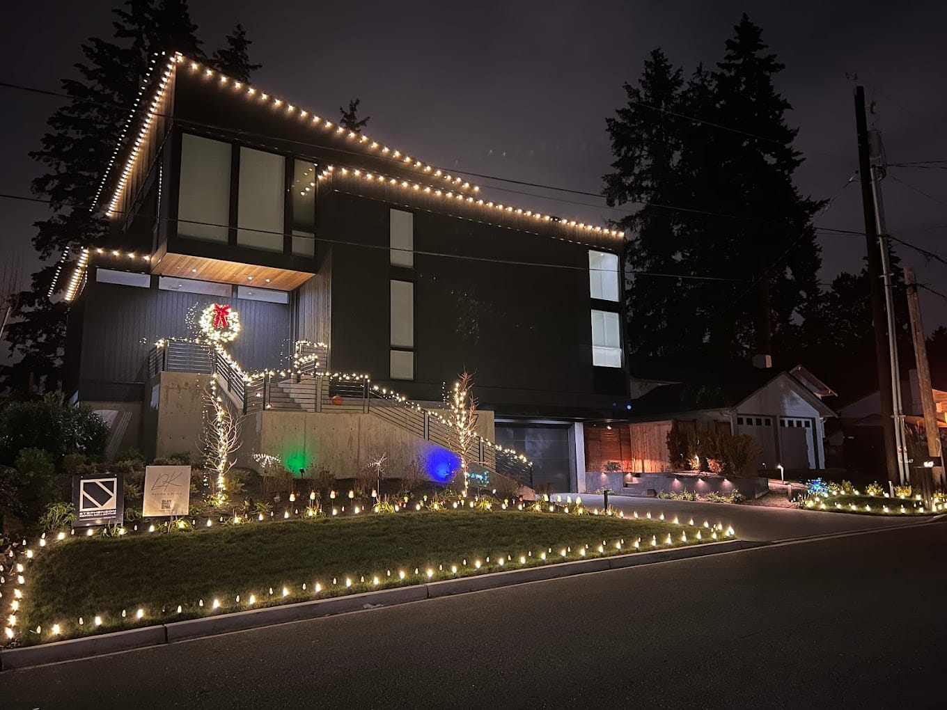 Modern home with landscape lighting, pathway lights, deck accent lighting, and wreath